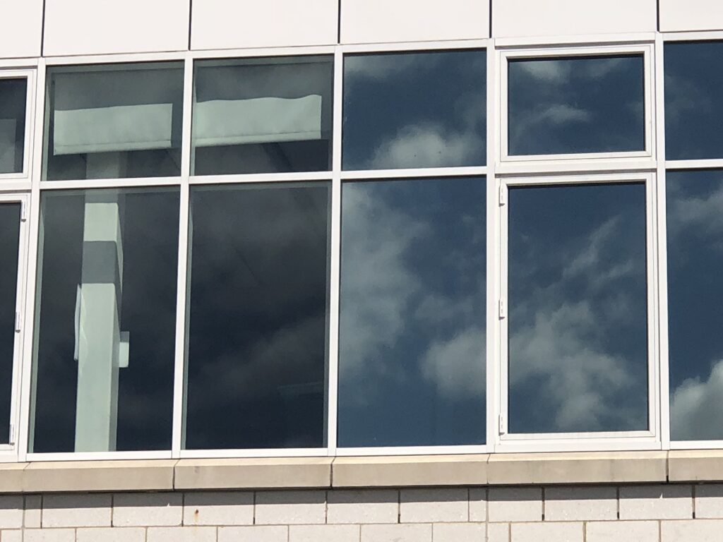 Solar Control Window Film Modernization – Thompson School District, Thompson CT Thompson School District building showing partial installation of solar control window film for a modernized, uniform appearance.